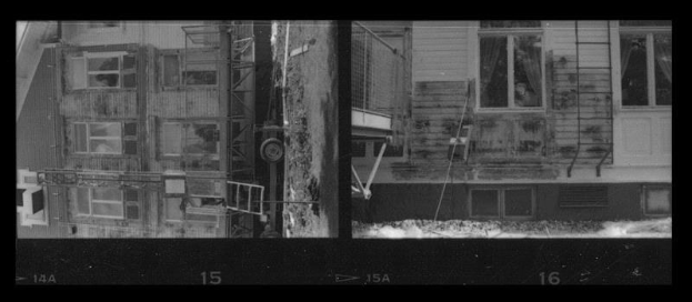 Schwarz-weißes Foto eines feuerbeschädigten Gebäudes mit Fenstern, Leitern und nummerierten Standortmarkierungen unten.