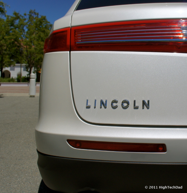 Ein Auto steht neben Zaunpfählen, Bäumen und Gebäuden.