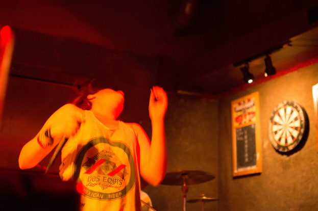 Eine Person tanzt mit einem Oberteil, rechts sind Lichter zu sehen.