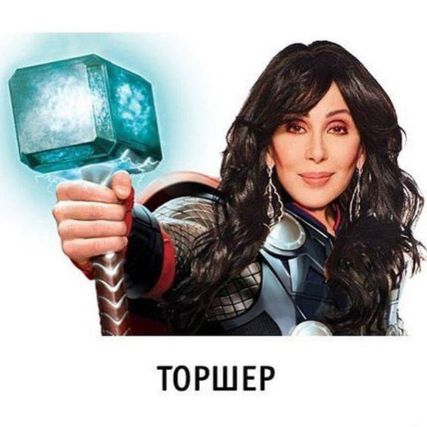 Eine Frau in einer Jacke hält einen Hammer vor ein Plakat.