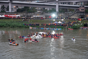 Eine Gruppe von Menschen in kleinen Booten auf einem Gewässer, umgeben von Vegetation und Infrastruktur, tragen Rettungswesten während einer Rettungsaktion.