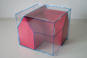 Ein pinker und blauer Wahlurne mit offenem Deckel auf einem weißen Tisch stehend, an einer Wand lehnend.