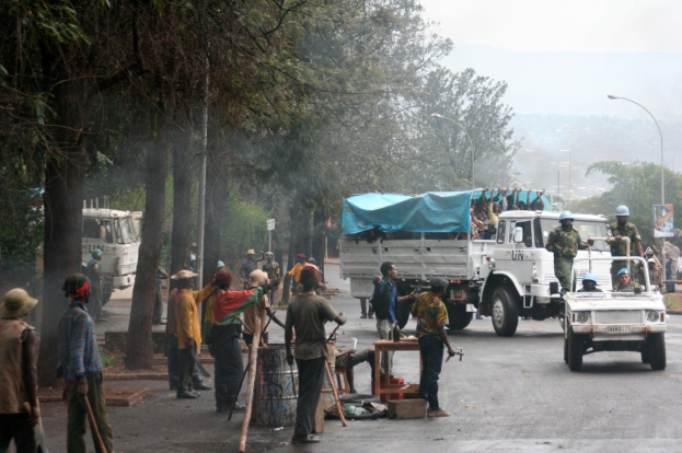 Arbeiter führen Aufgaben neben einer Straße durch, während ein Lkw mit einer großen Menge in der Nähe steht und Officer in einem Fahrzeug die Straße entlangfahren, umgeben von Bäumen und Straßenlaternen.