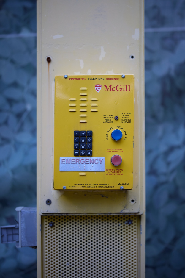 Gelber Notrufknopf an einer Gebäudewand angebracht, mit Tasten und Text für Notrufe.