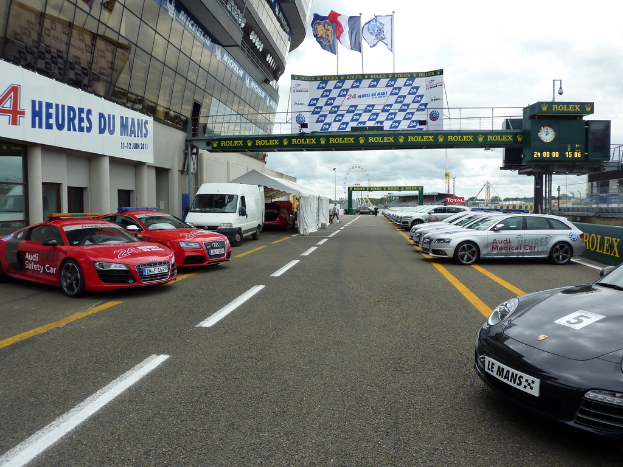 Autos sind vor einem Gebäude auf der rechten Seite geparkt, mit Bannern auf der rechten Seite.