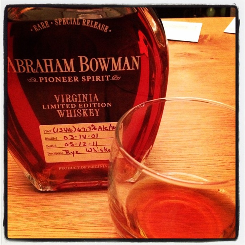 Ein Tisch mit einer Flasche Whiskey, einem Glas und Papieren im Hintergrund.