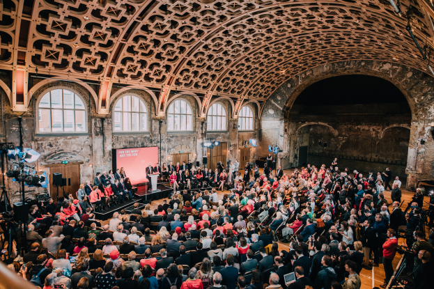 Eine große Gruppe von Menschen sitzt in einem Raum mit einer Bühne, Kameras auf der linken Seite und Text, der das Londoner Filmfestival 2019 anzeigt.