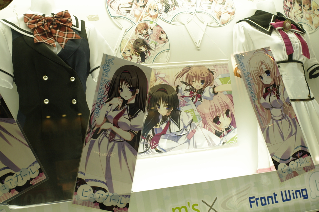 Schaufensterpuppen in verschiedenen Outfits mit Cartoon-Bildern an der Wand dahinter.