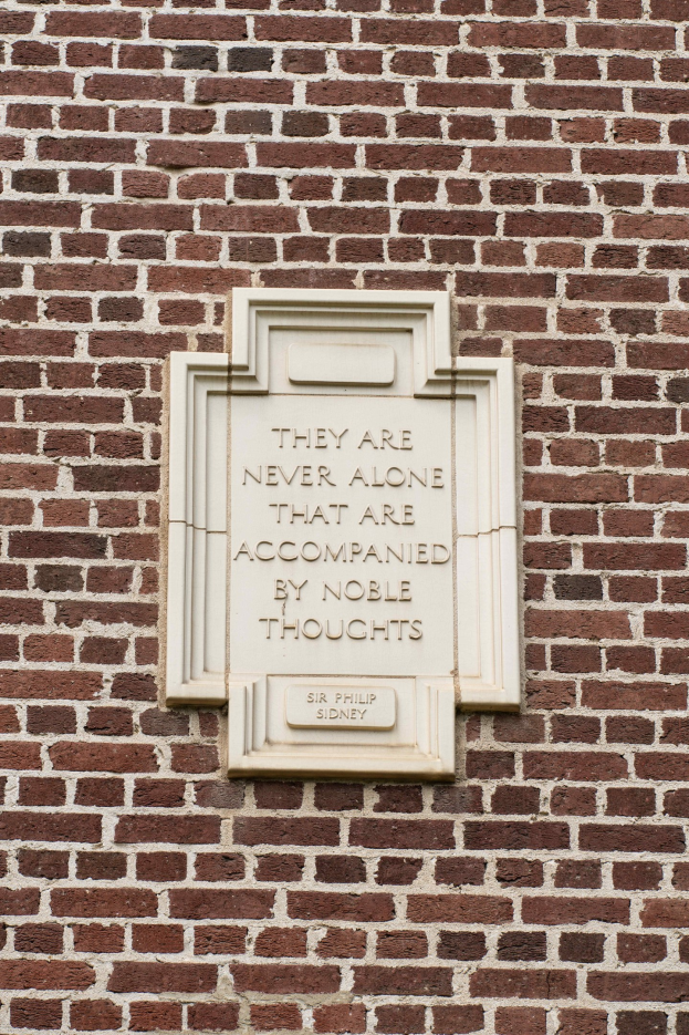 Steintafel auf einer Ziegelwand mit der Inschrift "Sie sind nie allein, die von edlen Gedanken begleitet werden."