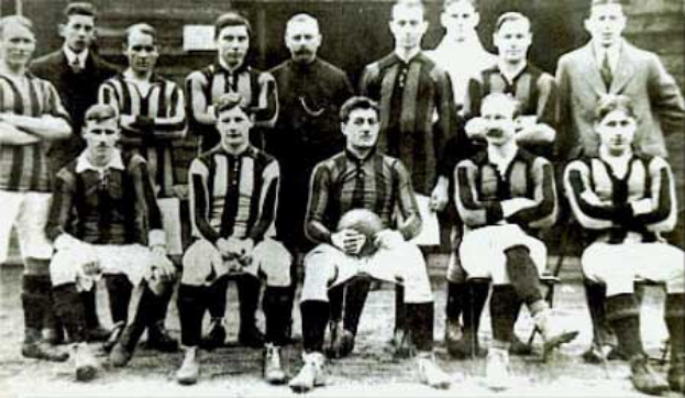 Ein Schwarz-Weiß-Foto einer Fußballmannschaft, bei der einige Spieler stehen und andere sitzen, vor einer Wand, mit dem Text "Ballymena Football Club" unten.