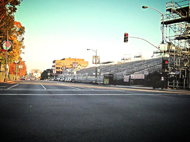 Eine Straße mit einer Verkehrsampel und Equipment auf der rechten Seite, Warnschilder und mehrere Fahrzeuge vor zahlreichen Bäumen auf der linken Seite.