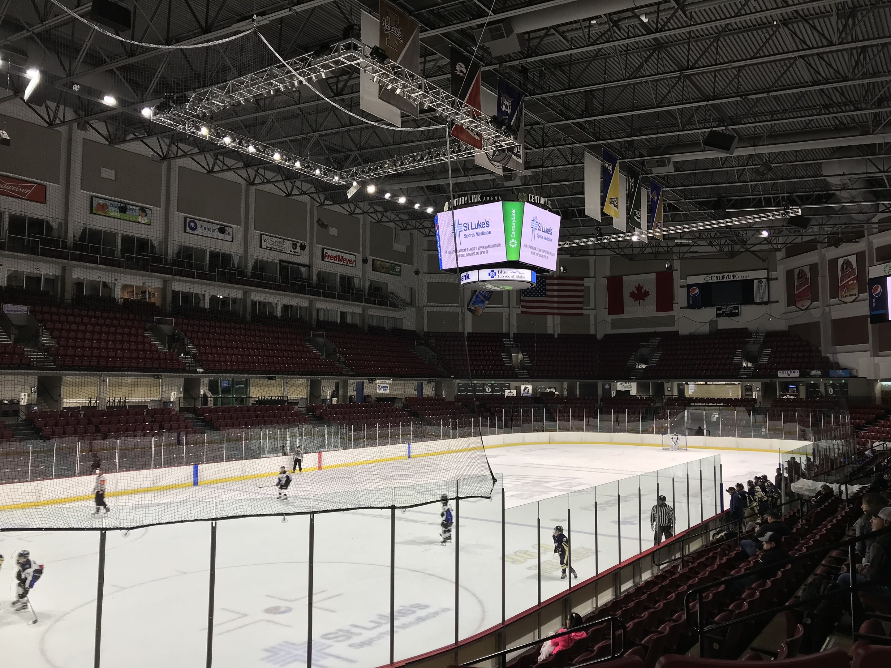 Ein Hockey-Spiel in einer großen Arena mit einem zentralen Netz, Zuschauern auf beiden Seiten und Bannern an den Wänden unter einer beleuchteten Decke.