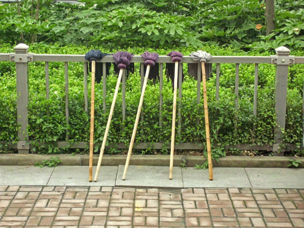 Mehrere Mops sind auf einem Geländer mit Pflanzen im Hintergrund zu sehen.