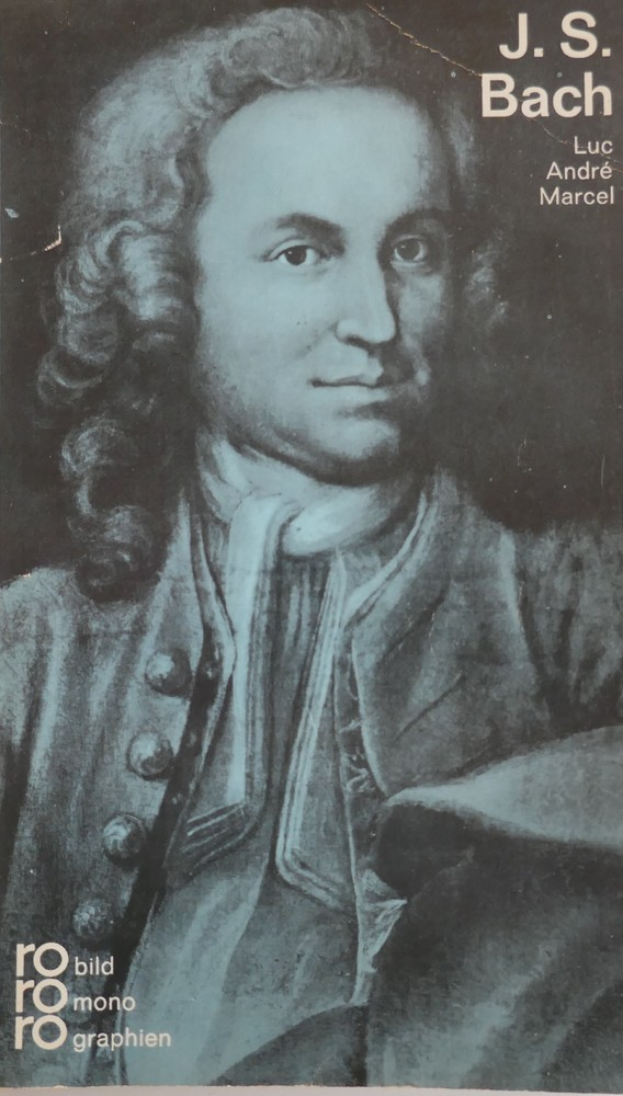 Ein Plakat mit einem ernst dreinblickenden Mann mit dunklem Haar, der einen Anzug trägt und die Schrift 'J.S.' in fetter schwarzer Schrift.