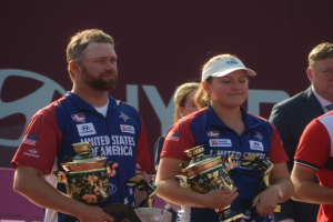 Gruppe von Menschen, die Pokale halten, mit einem "Weltarcherie-Meisterschaften"-Schild im Hintergrund.