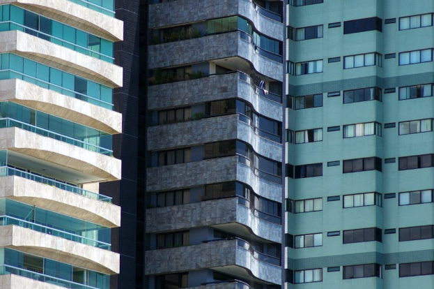 Mehrere Gebäude in unterschiedlicher Höhe und Gestaltung sind in einer städtischen Umgebung zu sehen.