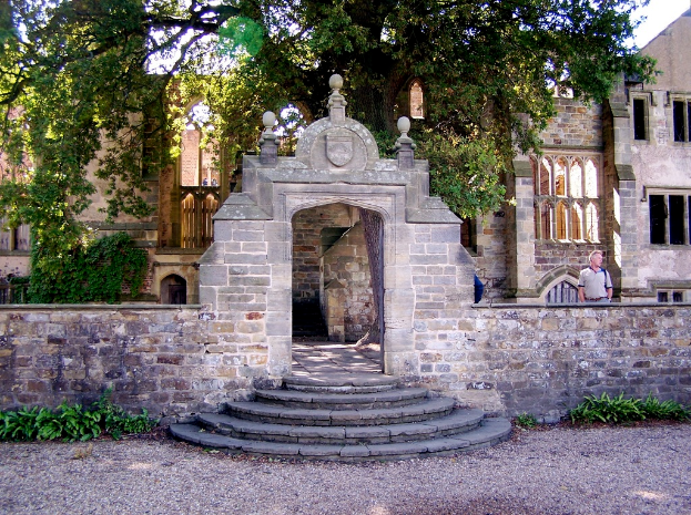 Ein altes Gebäude mit einem Mann auf der rechten Seite und Bäumen im Hintergrund.