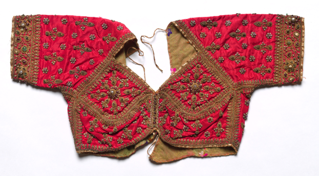 Ein rotes Oberteil mit goldener Stickerei mit detaillierten Designs, das gegen einen weißen Hintergrund gezeigt wird.