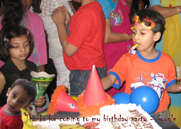 Kinder vor einem Tisch mit Kückchen, Luftballons und Mützen, hinter ihnen stehen Erwachsene.