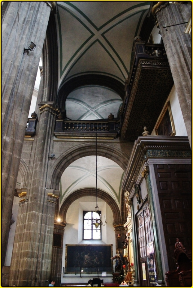 Ein Innenblick eines Palasts mit Schränken, beleuchteten Säulen, Wandskulpturen, einem großen Rahmen und einer von der Decke hängenden Lampe.