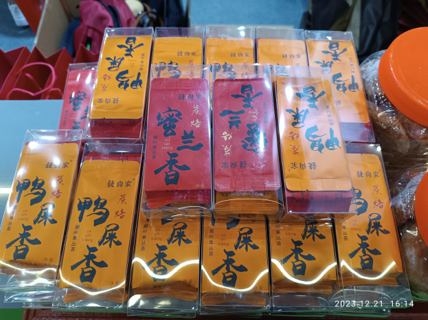 Ein Tisch voller verschiedener Lebensmittel, Packungen, Schachteln und Taschen während eines chinesischen Neujahrsfestes, mit einer Person im Hintergrund.