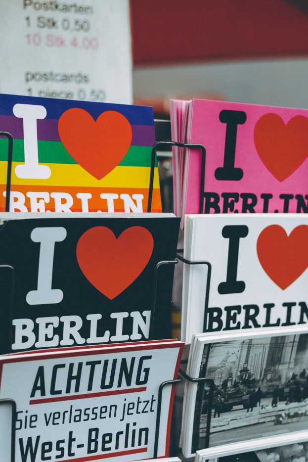Ein Regal mit verschiedenen Büchern und Postern mit der Aufschrift "Ich liebe Berlin", vor einem leicht unscharfen Hintergrund.