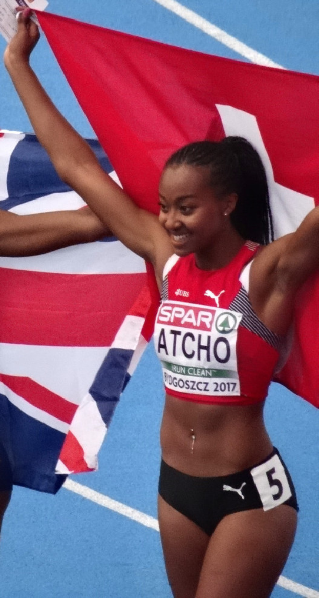 Eine Frau in einem Sportoutfit steht auf einer Bahn und hält eine britische Flagge.