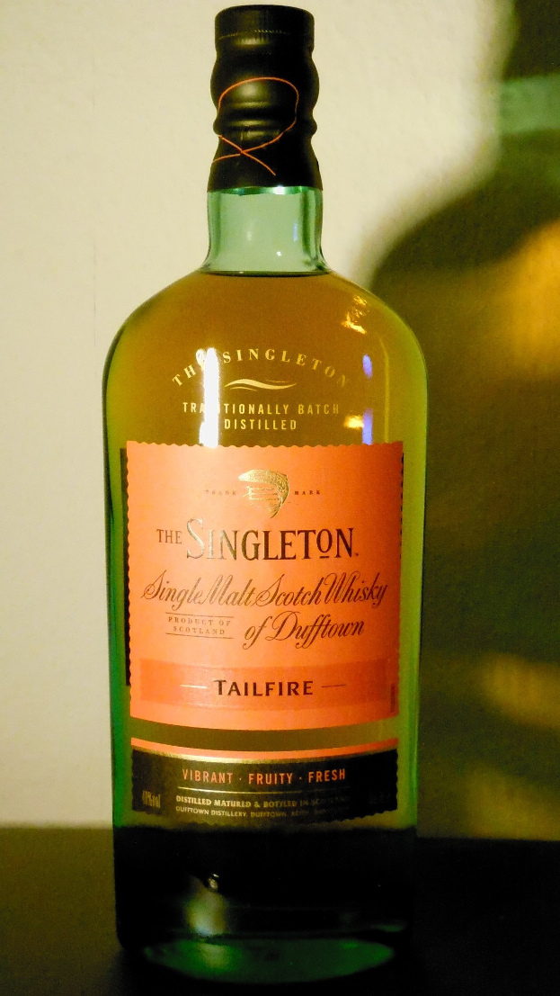 Eine tiefe bernsteinfarbene Flasche Singleton of Dufftown Tailfire Single Malt Scotch Whisky mit einem schwarzen Etikett, das eine Löwenkrone und ein Schloss zeigt.