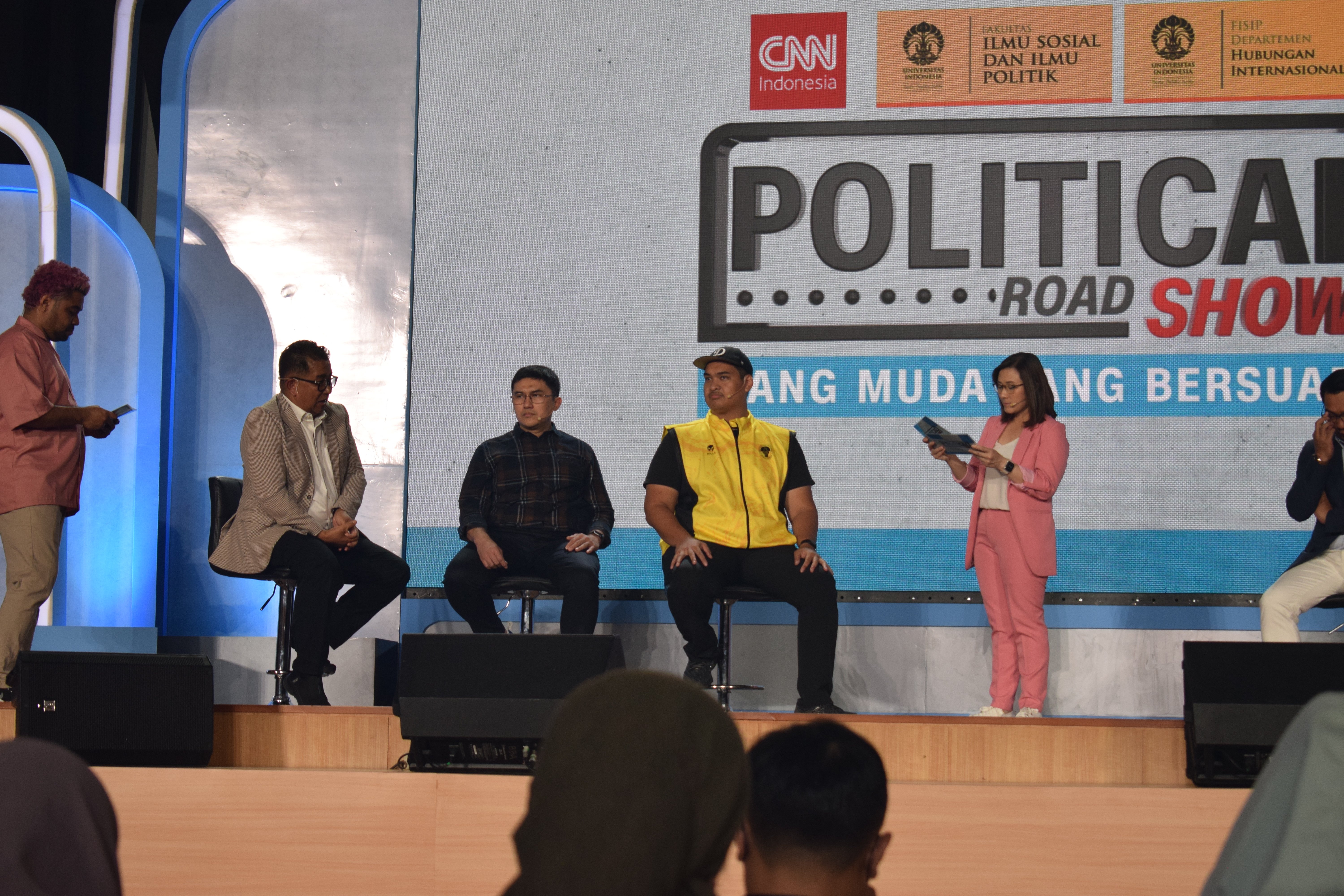 Eine Gruppe von Menschen sitzt auf einer Bühne mit einigen, die auf dem Podium davor stehen, und ein Schild im Hintergrund mit der Aufschrift "Cnn Political Road Show".