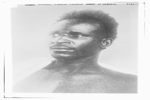 Ein Schwarz-Weiß-Foto eines Mannes mit ernster Miene, mit dem Text "Seneg Verletzter französischer Gefangener unter deutscher Herrschaft" oben.