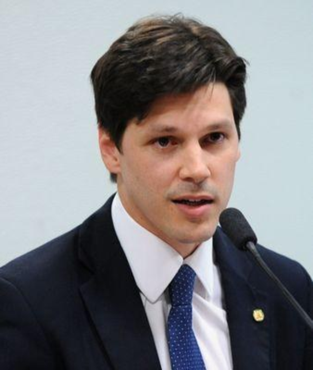 Ein Mann im Anzug spricht in ein Mikrofon und scheint eine Regierungsentscheidung zu kommentieren.