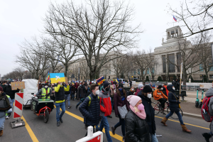 Eine große Gruppe von Menschen marschiert auf einer Straße in Washington, D.C. am 21. Januar 2020 mit Plakaten und Schildern, während einige Fahrräder fahren, Schilder, Bäume und ein klarer blauer Himmel im Hintergrund zu sehen sind.