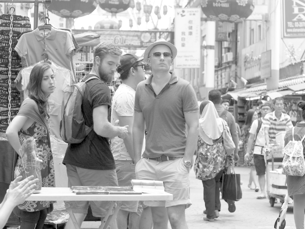 Ein belebter Marktplatz mit Ständen und Menschen auf beiden Seiten und Plakaten in der Mitte.