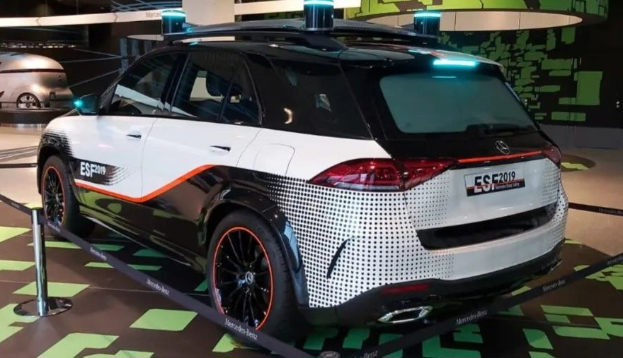 Mercedes-Benz E-Klasse Electric SUV auf der IAA in Frankfurt umgeben von Absperrpollern mit Seilen und Lichtern, mit einem weiteren Fahrzeug und einer textbedruckten Wand im Hintergrund.