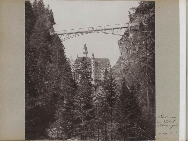 Ein Schwarz-Weiß-Foto der Neuschwanstein Burg in Deutschland mit einer Brücke im Vordergrund, umgeben von Bäumen und Text auf der rechten Seite.