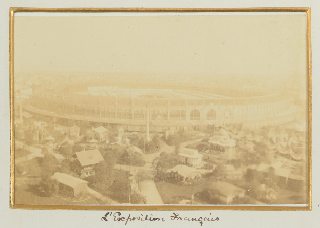 Altes Schwarz-Weiß-Foto eines Stadions in einer städtischen Umgebung mit umliegenden Gebäuden, Bäumen und Strommasten; Text erscheint unten auf dem Bild.