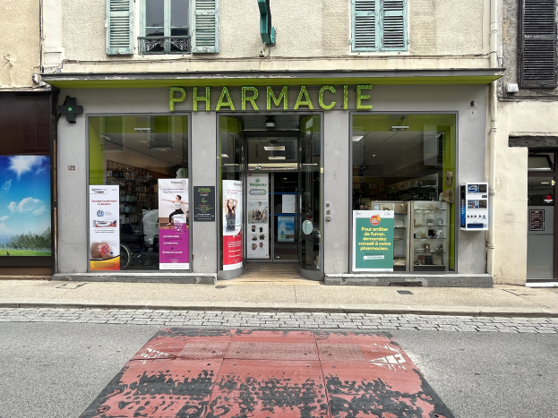 Apotheke mit Glaswänden und -türen, Plakate an den Wänden, an der Ecke einer Straße mit einer Straße unten.