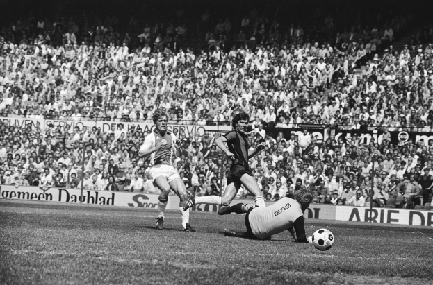 Schwarzes und weißes Foto von Männern, die auf einem Feld Fussball spielen, mit Zuschauern im Hintergrund und einer "Bundesliga 1978-79 Ajax 1-1 Hannover 96"-Aufschrift.