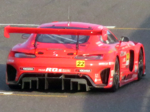 Roter Porsche 911 GTS Rennauto auf einer Rennstrecke mit aerodynamischem Design, großem Heckspoiler und Flügel, schwarzen Rädern und leistungsstarkem Motor.