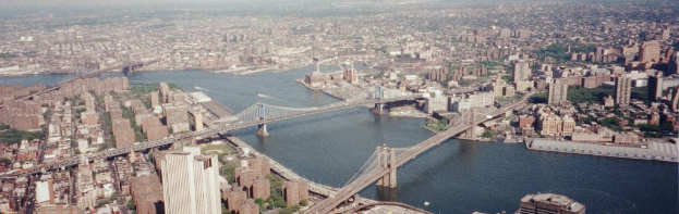 Eine Stadtansicht mit Gebäuden, Bäumen, Brücken und einem Gewässer.