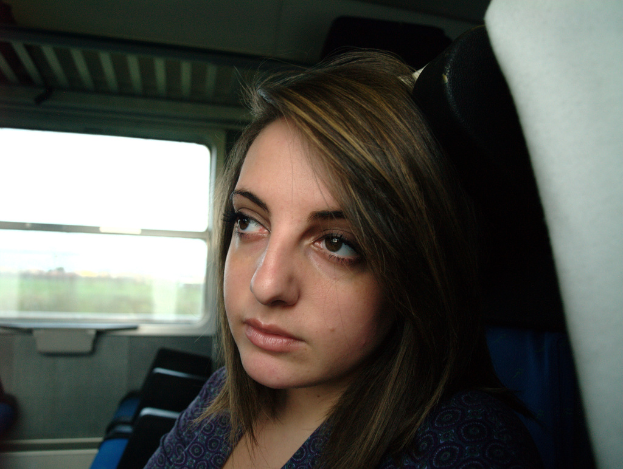 Eine Frau steht in der Mitte des Bildes mit einem Glasfenster auf der linken Seite.