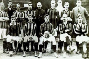 Ein Schwarz-Weiß-Foto einer Fußballmannschaft, bei der einige Spieler stehen und andere sitzen, vor einer Wand, mit dem Text "Ballymena Football Club" unten.