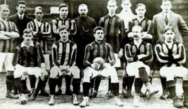 Ein Schwarz-Weiß-Foto einer Fußballmannschaft, bei der einige Spieler stehen und andere sitzen, vor einer Wand, mit dem Text "Ballymena Football Club" unten.