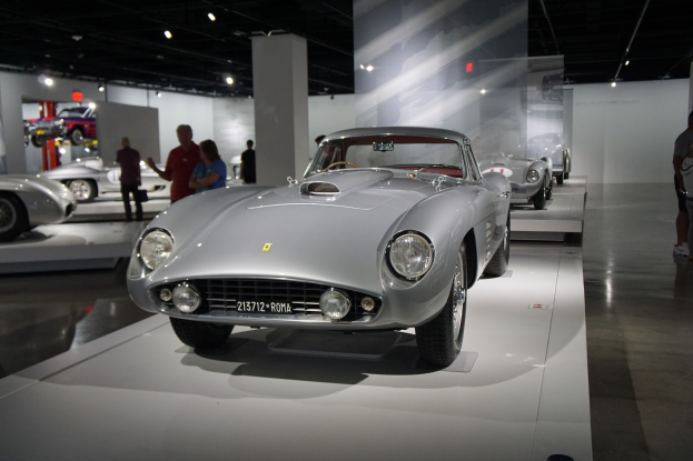 Roter Ferrari 250 GT California Spyder im Ferrari-Museum in Rom ausgestellt, Besucher bewundern seine klassische Gestaltung unter Deckenbeleuchtung.