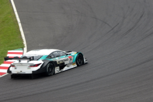 Ein Mercedes-AMG GT3-Rennwagen fährt auf einer Rennstrecke mit Text auf der Karosserie und Gras auf der linken Seite.