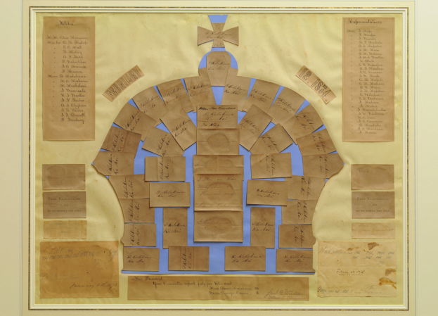 Ein Foto Rahmen zeigt einen Familienstammbaum mit einer Krone oben drauf, angeordnet in einem kreisförmigen Muster aus Karten mit Text.