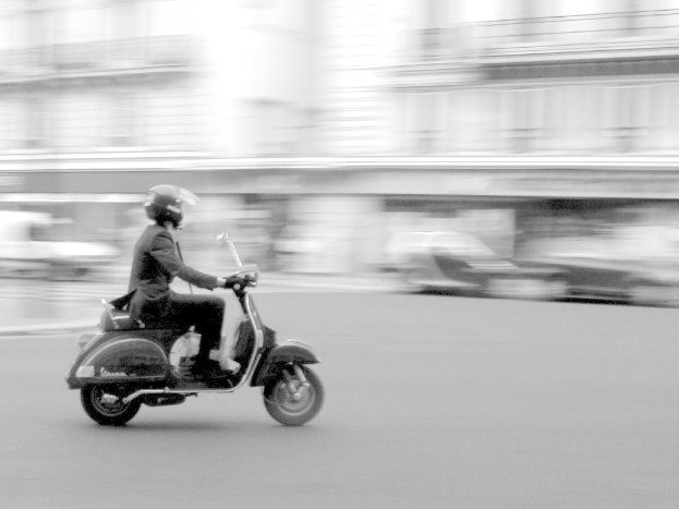 Eine Person mit einem Roller auf einer Straße.