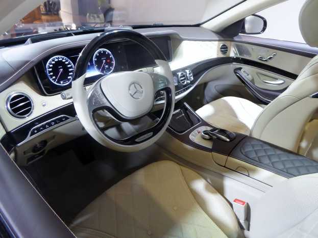 Das Innere eines Mercedes S-Klasse Limousinen zeigt ein luxuriöses Lenkrad, bequeme Sitze, ein elegantes Armaturenbrett mit verschiedenen Knöpfen und Bedienelementen und ein großes Touchscreen-Display.