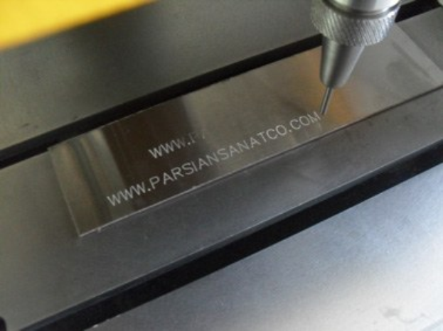 CNC-Fräsmaschine schneidet ein Metallobjekt mit eingraviertem Text.