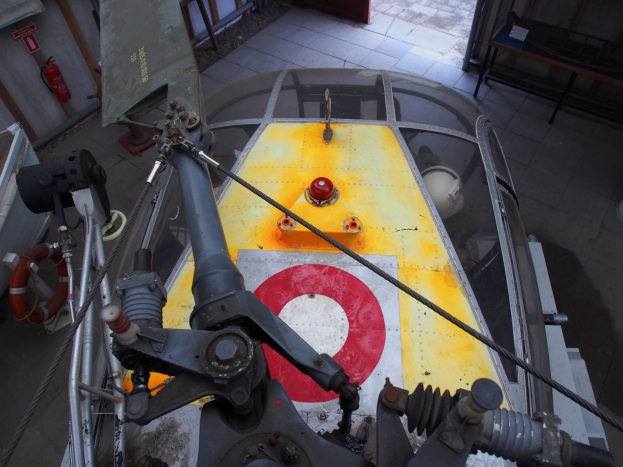 Nahaufnahme eines Hubschraubers auf einem Gebäudeboden während der Wartung, mit einem Feuerlöscher links und einer Bank rechts.